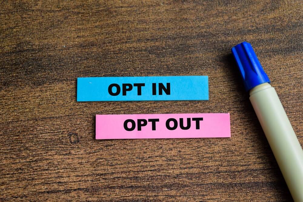 opt out and opt in on blue and pink papers on wooden table