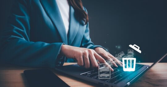 woman in suit jacket deleting data from website on laptop with floating icons