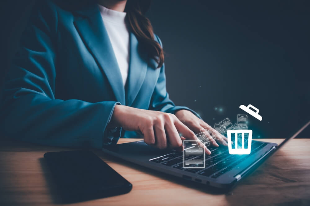 woman in suit jacket deleting data from website on laptop with floating icons