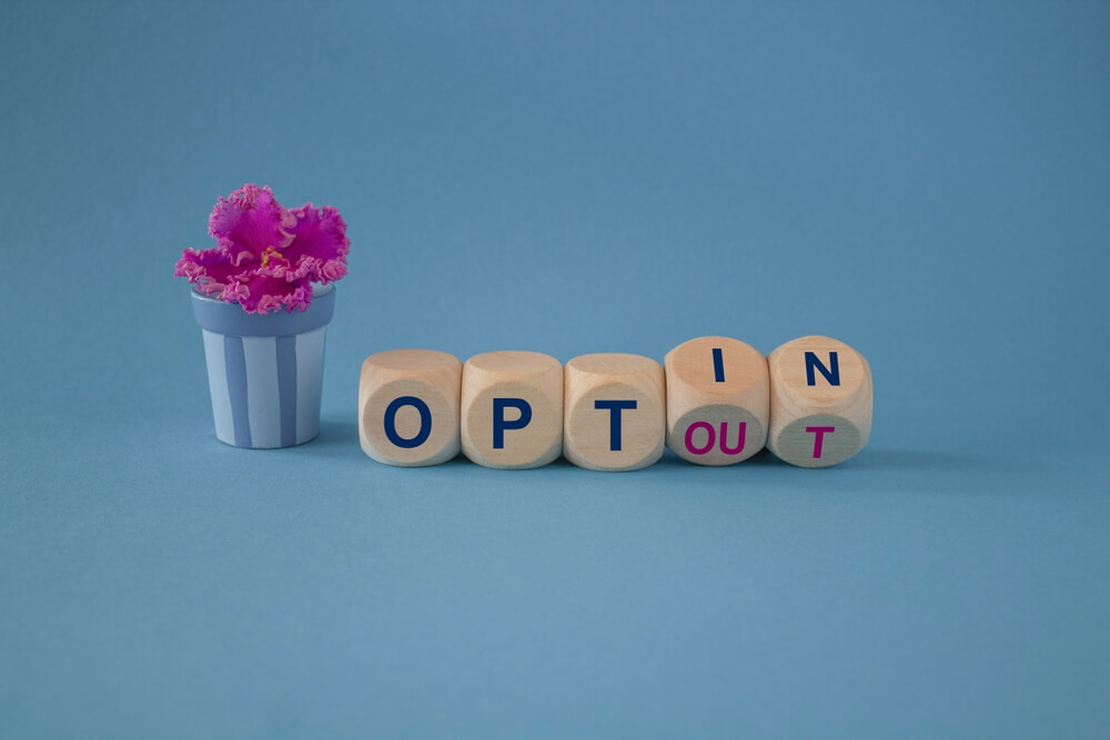 turned wooden cubes and changed concept words opt out to opt in with flower pot and blue background
