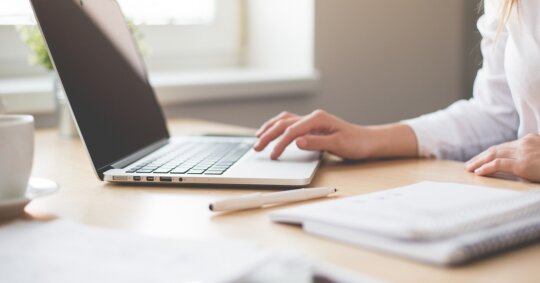 woman at laptop with coffee mug performing Intelius opt out