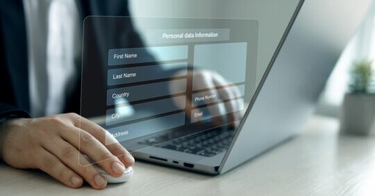 Person using a laptop with a digital overlay showing a personal data information form, symbolizing online privacy and USPhoneBook opt out.