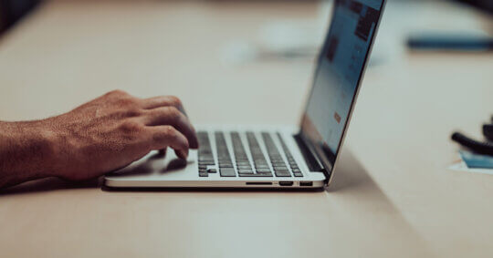 Close-up of a person using a laptop as they try to navigate the ZoomInfo opt-out process manually.