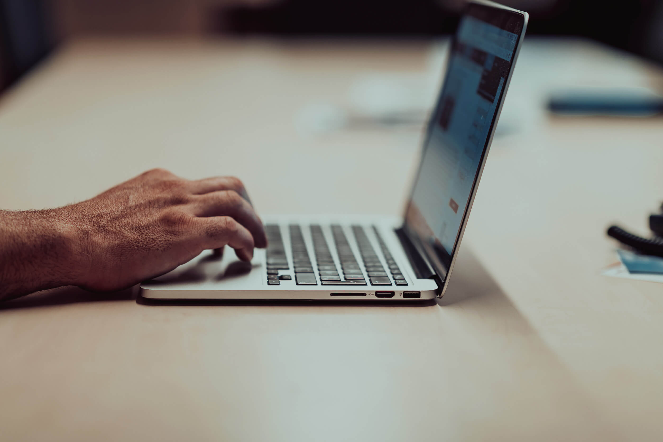 Close-up of a person using a laptop as they try to navigate the ZoomInfo opt-out process manually.