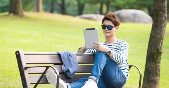 A young man using a computer on a park bench after learning about the IDTrue opt out process.